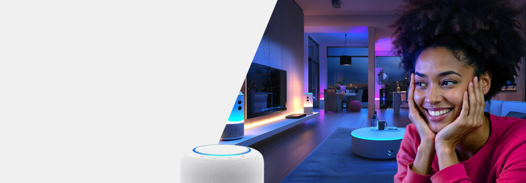 Smiling woman in a pink top sits with her hands on her cheeks. She is in a modern living room with colorful ambient lighting. A smart speaker and TV are visible in the background.
