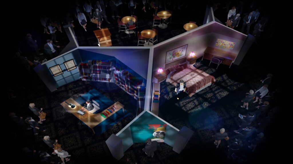 An overhead view of a diorama depicting two rooms. The left room has shelves with colorful books and a person working at a desk. The right room features a bed, paintings, and a person standing. People surround the diorama, observing it.