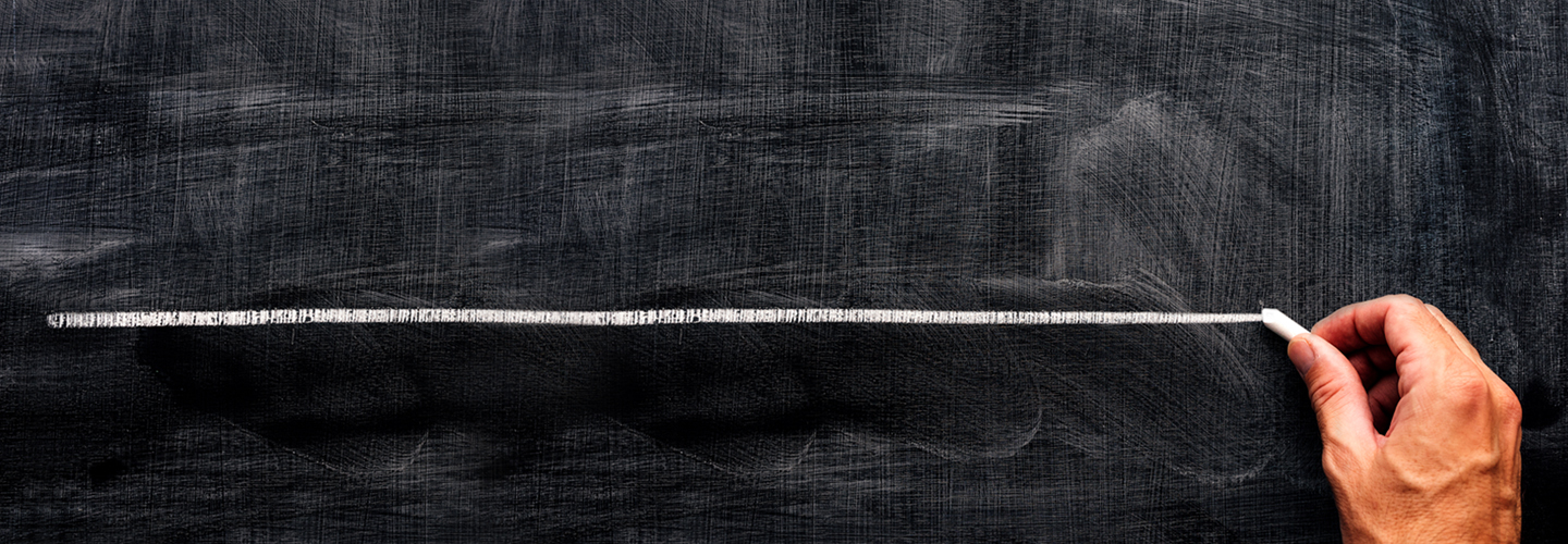 A hand draws a straight white line across a dusty blackboard, echoing the precision of Roches new comprehensive training program. The chalk leaves smudges and marks, signifying the thorough exploration of every detail.