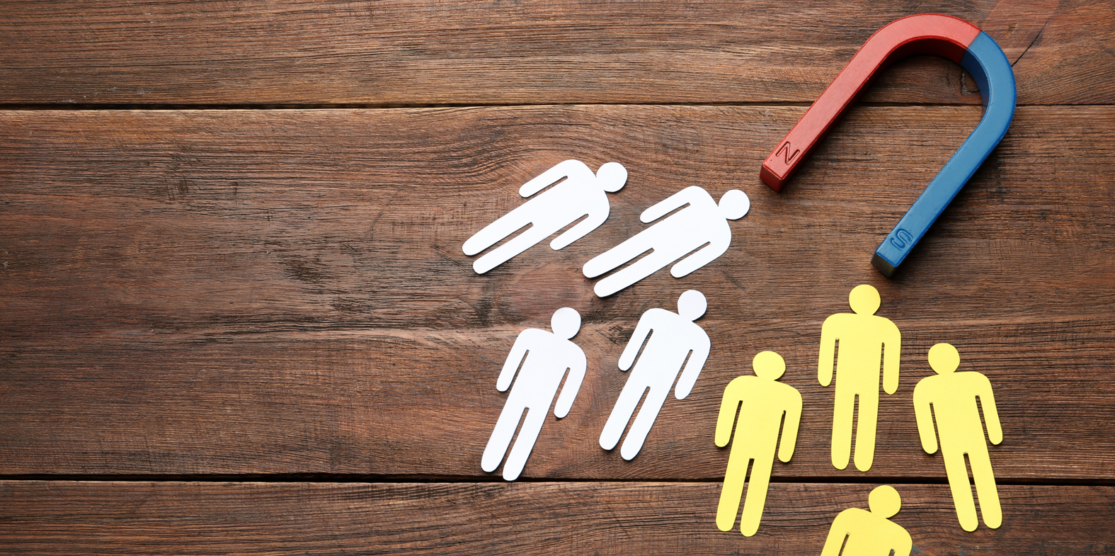 Magnet attracting people traffic on wooden background, top view with space for text.